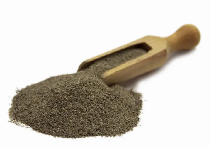 Stos mielonego pieprzu czarnego 1kg na drewnianej łyżce, gotowy do przyprawienia potraw.