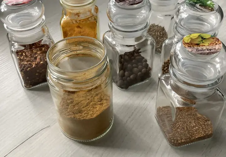 Słoiczki z przyprawami: płatki chili, kurkuma, kmin rzymski, kolendra, gorczyca i inne, idealne do przygotowania aromatycznego curry.