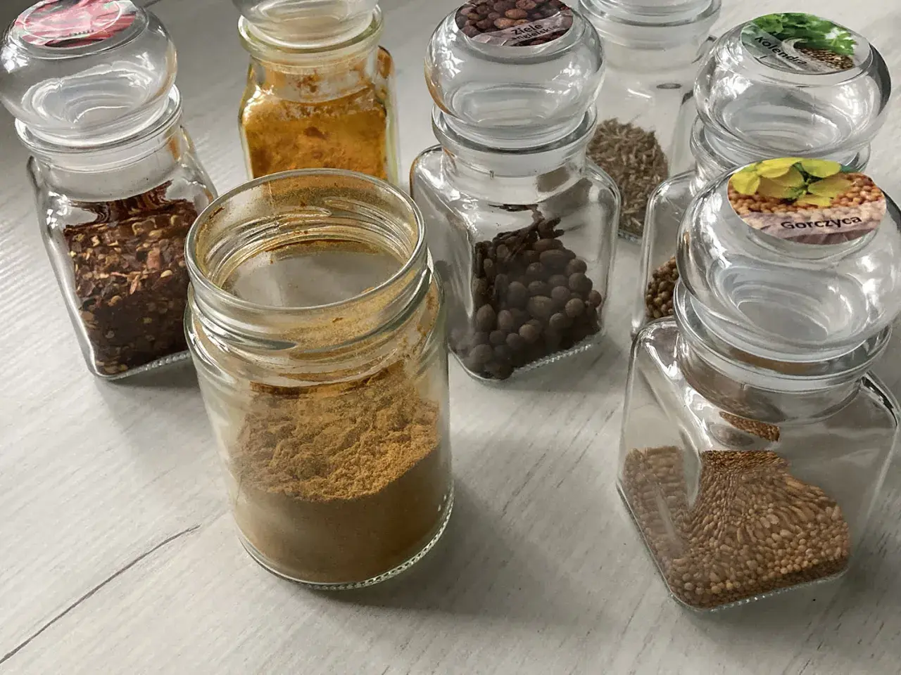 Słoiczki z przyprawami: płatki chili, kurkuma, kmin rzymski, kolendra, gorczyca i inne, idealne do przygotowania aromatycznego curry.
