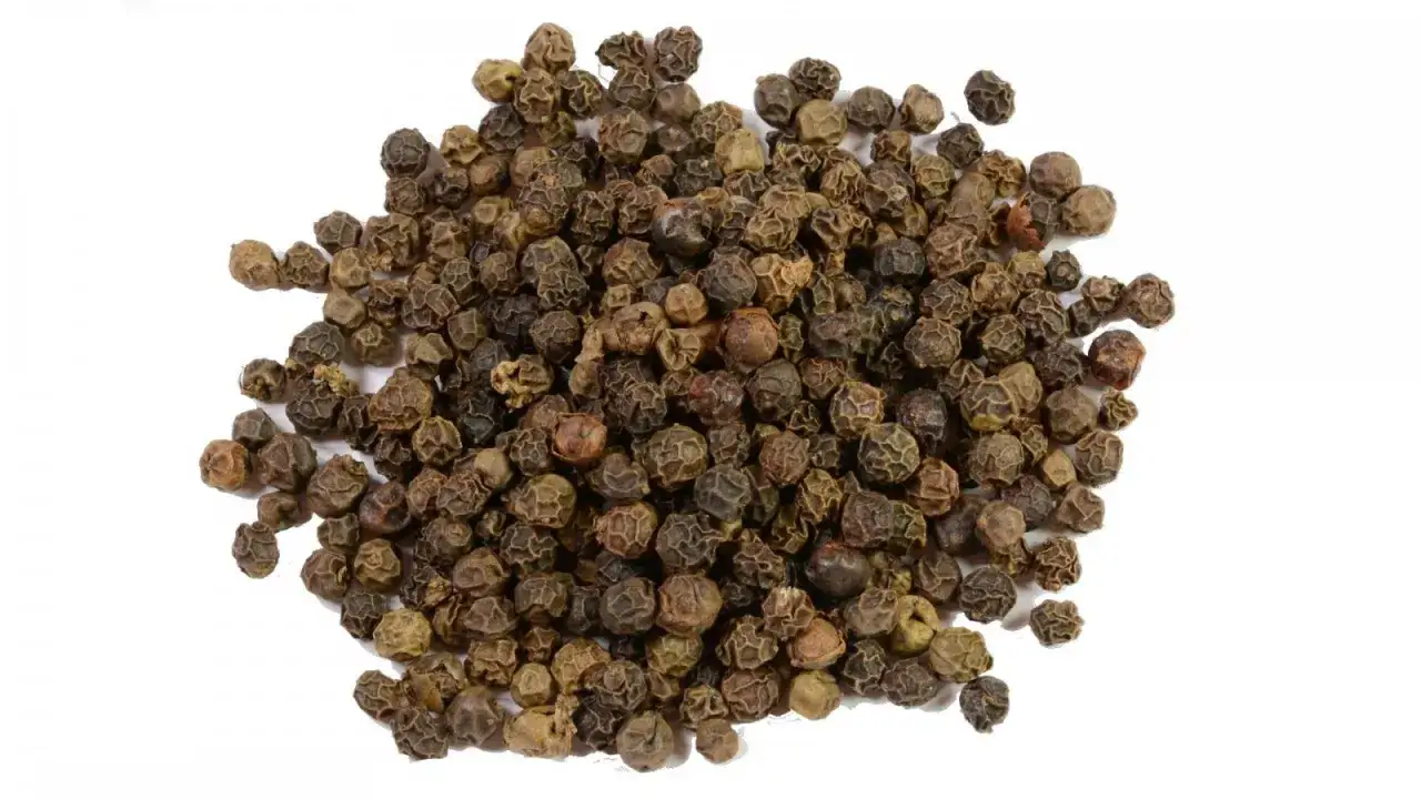 Kupa całych ziaren pieprzu czarnego mielonego, gotowa do dodania aromatu do potraw.